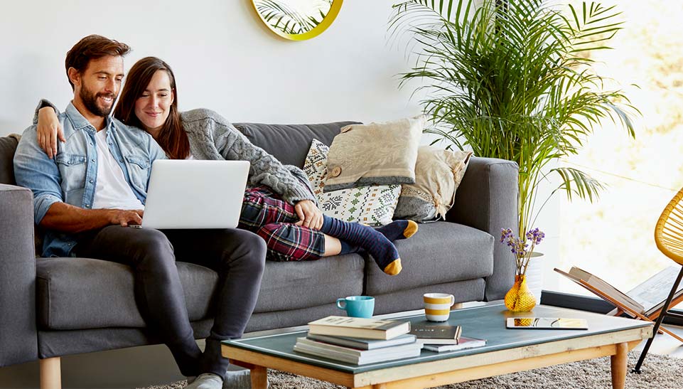 Couple on a couch looking at a laptop